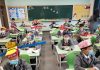 Crianças chinesas usam chapéus na escola para manter distanciamento social e evitar propagação do coronavírus.