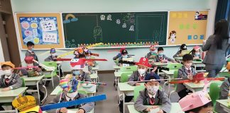Crianças chinesas usam chapéus na escola para manter distanciamento social e evitar propagação do coronavírus.