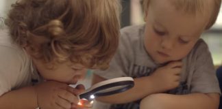 Imagem do documentário "O começo da vida" mostra duas crianças, uma delas segura uma lupa, para ilustrar matéria que fala de documentários sobre infância e educação.
