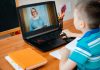 Menino de camisa azul listrada assiste a aula no computador. A improvisação do ensino imposta pela quarentena pode interferir na saúde mental e emocional das crianças.