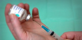 Mãos seguram seringa de vacina para ilustrar matéria sobre risco de coronavírus atrapalhar a vacinação contra o sarampo.