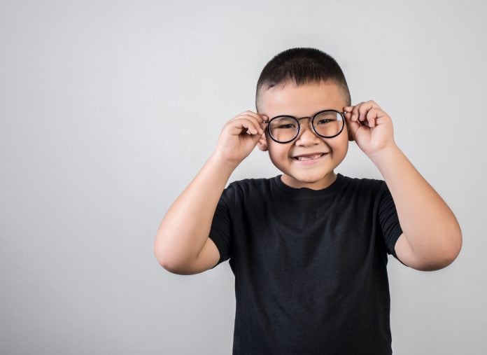 Criança com óculos de grau; casos de miopia aumentam e podem ter relação com uso de telas e permanência em ambientes fechados.