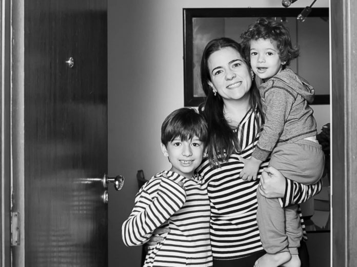 Mãe e seus dois filhos posam na porta de casa para fotógrafa que fez homenagem no Dia das Mães.