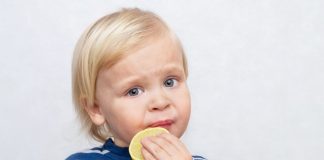 Alimentos azedos e amargos como o limão, que a criança loirinha está chupando nesta imagem, devem ser introduzidas na dieta da criança desde muito cedo.