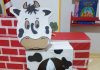Caixa de supermercado se transforma em vaquinha de papelão banca com manchas pretas e uma luva descartável remete às tetas da vaca para que a criança brinque de tirar leite dela.