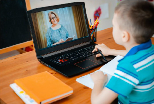 Menino de camisa azul listrada assiste a aula no computador. A improvisação do ensino imposta pela quarentena pode interferir na saúde mental e emocional das crianças.