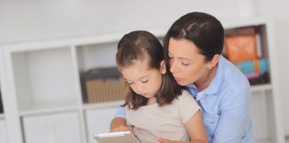 Mãe e filha leem livro digital em tablet, ilustrando matéria sobre como conversar sobre pandemia com crianças.