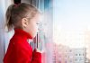 Criança olha para fora por um janela em meio à pandemia de coronavírus, em imagem que ilustra matéria sobre saúde mental das crianças.