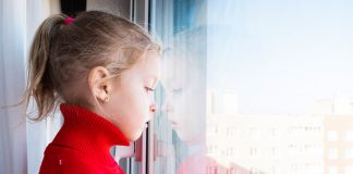 Criança olha para fora por um janela em meio à pandemia de coronavírus, em imagem que ilustra matéria sobre saúde mental das crianças.