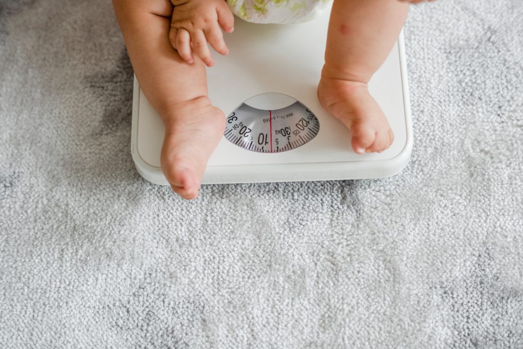 Bebê está em cima de balança para ilustrar matéria que fala sobre ligação entre dormir tarde e sobrepeso.