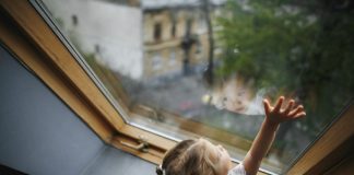 Criança em frente a uma janela, com olhar preocupado