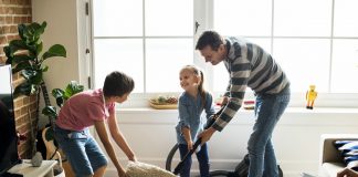 Filhos responsáveis devem aprender com os pais a ajudar nas tarefas da casa, como nessa imagem que os dois irmãos ajudam o pai a limpar a sala