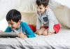 Interação social online, já que é para suar as telas, como os dois garotos da imagem que olham para um tablet na cama, melhor que seja de forma produtiva, para descobrir novas habilidades, por exemplo