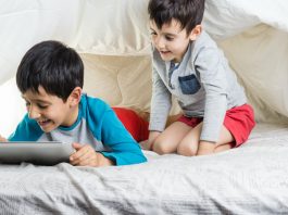 Interação social online, já que é para suar as telas, como os dois garotos da imagem que olham para um tablet na cama, melhor que seja de forma produtiva, para descobrir novas habilidades, por exemplo