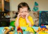 Como educar as emoções: se a criança chora, como essa da imagem de camisa amarela junto a seus dinossauros, os pais devem explicar a ela o motivo do choro
