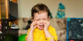 Como educar as emoções: se a criança chora, como essa da imagem de camisa amarela junto a seus dinossauros, os pais devem explicar a ela o motivo do choro