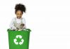 Consumo consciente: separar o lixo corretamente, como nesta imagem em que criança negra olha para lixeira somente com latas, é uma das ações que que os pais podem ensinar para as crianças para reduzir os impactos ao planeta