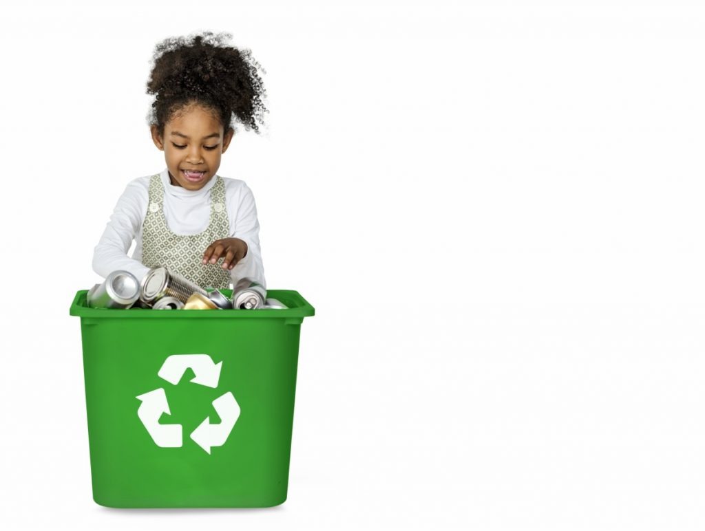 Consumo consciente: separar o lixo corretamente, como nesta imagem em que criança negra olha para lixeira somente com latas, é uma das ações que que os pais podem ensinar para as crianças para reduzir os impactos ao planeta