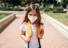 Surtos de covid-19 em escolas são registrados em alguns países, diz OMS; na imagem, garota com mochila nas costas e máscara olha para a câmera