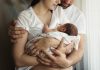 Pai e mãe estão abraçados e seguram um bebê no colo; Obstáculos para tornar a licença-maternidade mais longa no Brasil