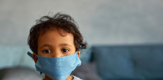 Menino usando máscara; imagem ilustra matéria sobre como proteger as crianças do coronavírus em locais públicos.