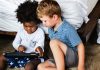 Duas crianças brincando com tablet, em ilustração à matéria sobre uso de telas.