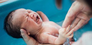 Intervenções durante o parto: saiba quais são e o que podem provocar na mãe e no bebê, como esse recém-nascido da imagem, que se vê somente os pés e a pulseira rosa de identificação