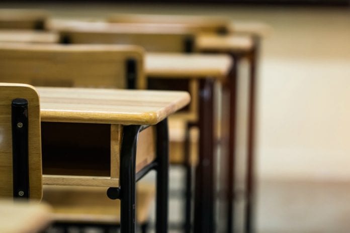Valor da mensalidade escolar pode aumentar até 10% se aprovado novo imposto, imagem mostra mesas e cadeiras de sala de aula vazia.