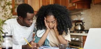 Famílias com crianças ou jovens são as mais afetadas pela pandemia; imagem mostra mulher e homem negros sentados em mesa que tem papeis e frutas
