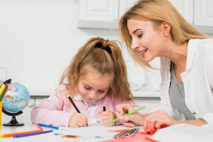 Mãe ajuda filha a fazer dever de casa, em ilustração à matéria que fala se os pais devem corrigir o dever de casa dos filhos.