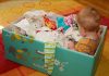 Pedro Fernando Nery fala sobre primeira infância e políticas públicas; imagem mostra caixa de papelão da Finlândia com bebê dentro e itens para seu uso