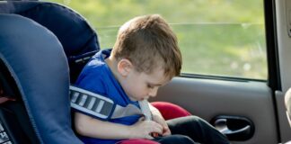 Lei da cadeirinha: saiba o que pode mudar no transporte de crianças; imagem mostra garoto sentado em cadeirinha dentro do carro, prendendo o cinto da mesma