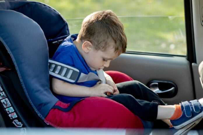 Lei da cadeirinha: saiba o que pode mudar no transporte de crianças; imagem mostra garoto sentado em cadeirinha dentro do carro, prendendo o cinto da mesma