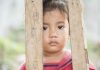 Violência contra crianças é altíssima em cidades como SP e RJ; menina pequena olha através de 'grades' de madeira