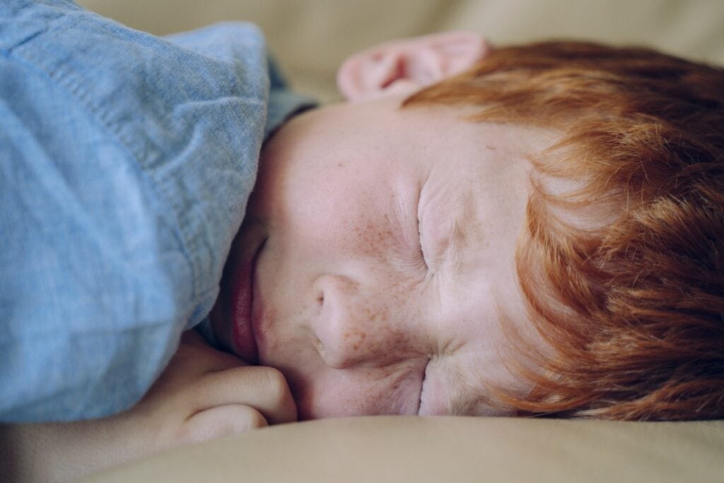 Terror noturno e pesadelo: saiba quais são as diferenças; imagem mostra menino de cabelos ruivos deitado com os olhos fechados apertados