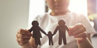 Quem 'devolve' a criança para adoção deve ser punida legalmente?; imagem mostra criança segurando 3 bonecos de papel que representam mãe, pai e filho
