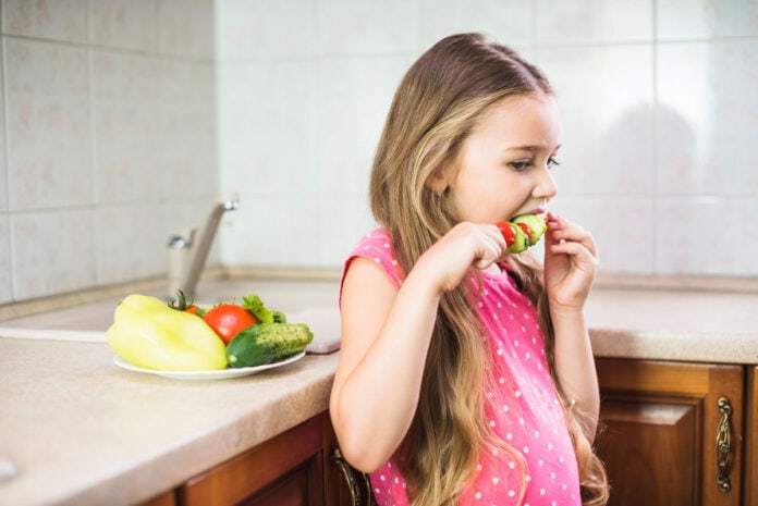 Alimentação vegana não é contraindicada às crianças; imagem mostra criança comendo vegetais