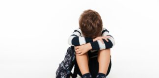 Por que a punição e o castigo não devem ser usados com as crianças;, imagem mostra menino sentado no chão com joelhos dobrados e rosto escondido sobre eles