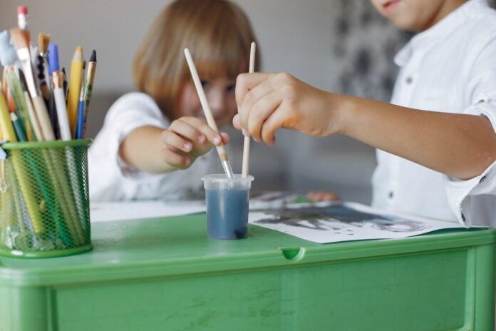 25% das escolas privadas reabriram em São Paulo, para atividades extracurriculares; imagem mostra duas crianças pitando desenho sobre carteira escolar verde