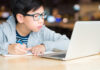 Resolução do CNE aprovada hoje permite aulas online até o fim de 2021; imagem mostra garoto de cabelo preto e óculos olhando para tela de computador