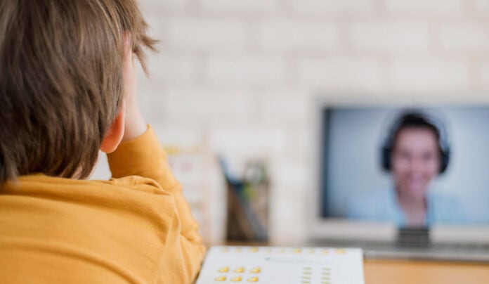 criança assistindo aulas de ensino remoto