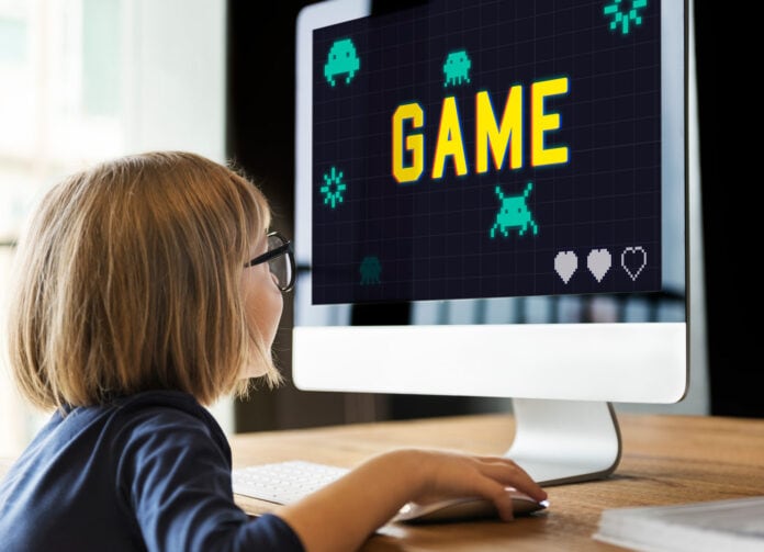 Menino olhando para um computador com um jogo, que pode ser usado como forma de gamificação na educação