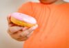 Obesidade infantil aumenta risco de fraturas em idade escolar; imagem mostra peito e barriga de menino gordo segurando um donut coberto de morango