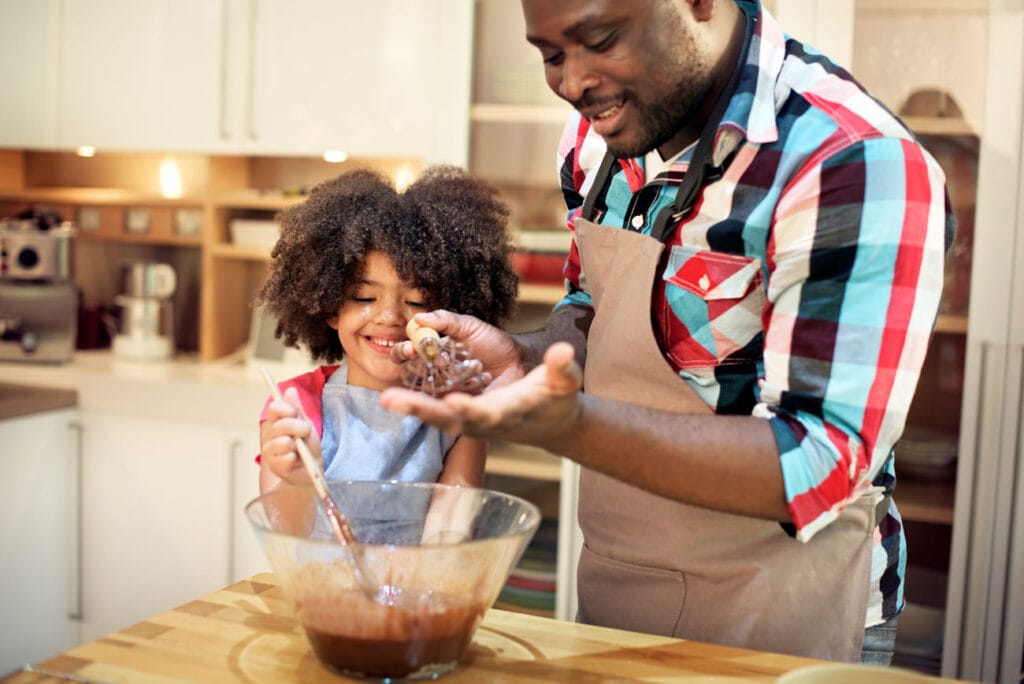 Pai e filha cozinhando juntos, uma das atividades para o Dia das Crianças
