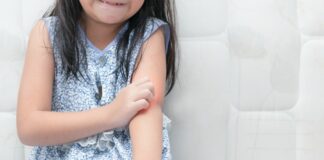 Psoríase em crianças: entenda a doença e as formas de tratamento; imagem mostra menina sentada no chão coçando cotovelo