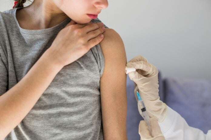 Vacina ampla contra meningite entrará no calendário de imunização do SUS; imagem mostra a mão com luva cirúrgica passando algodão em braço de garota de camiseta cinza