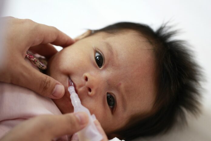 Mais de 60% das crianças não receberam a vacina contra a poliomielite; imagem mostra bebê recebendo vacina por gotinha