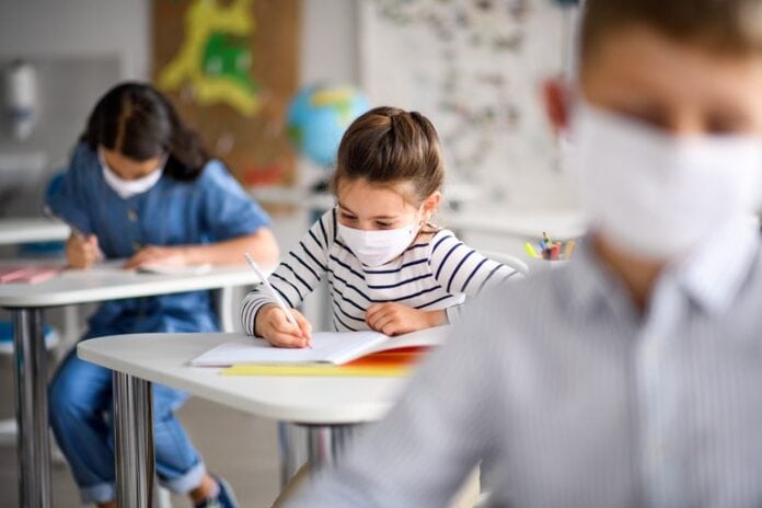 Pediatras assinam carta de apoio ao retorno das aulas presenciais; Criança na sala de aula com máscara