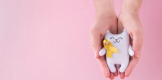Câncer infantil: diagnóstico precoce é essencial apra aumentar as chances de cura; imagem msotra gatinho branco de tecido com laço amarelo em fundo de imagem rosa