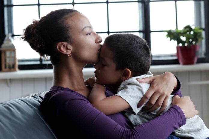 3 passos para ajudar a fortalecer a autoestima do seu filho; imagem mostra mãe com filho no colo beijando sua testa